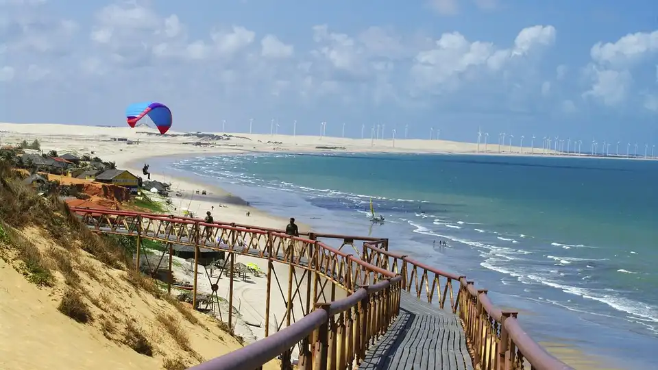 Falésias de Canoa Quebrada — passarela sobre penhascos com parapente e mar turquesa no litoral cearense