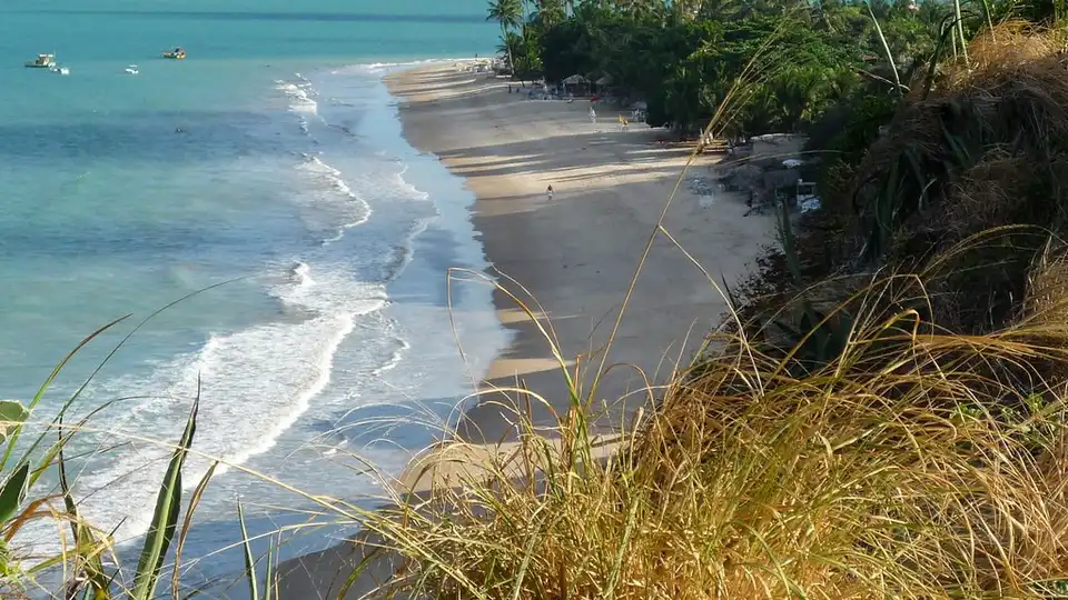 Praia da Ponta do Seixas em João Pessoa, PB — faixa de areia curva, coqueirais e mar turquesa vistos do alto