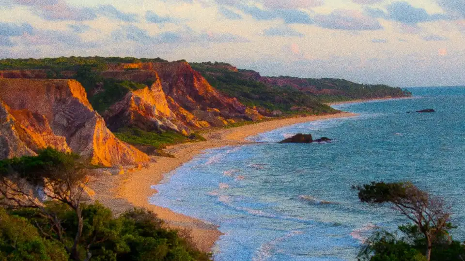 Praia de Tambaba no Conde, PB — falésias coloridas, faixa de areia e mar azul ao entardecer