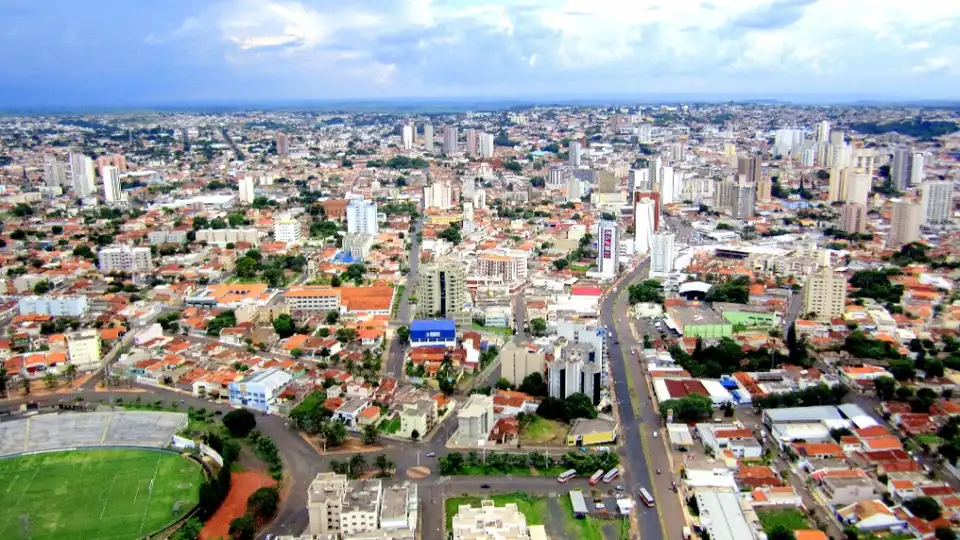 Vista aérea de Uberaba, MG — estádio, avenidas e o contraste entre casas de telhado cerâmico e edifícios altos