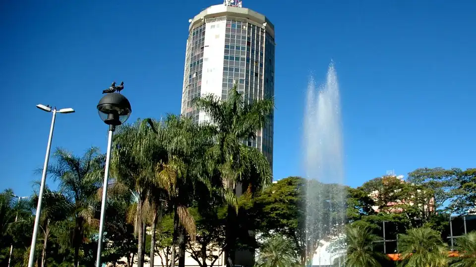 Praça Tubal Vilela em Uberlândia, MG — fonte, palmeiras e o edifício cilíndrico ao fundo sob céu azul